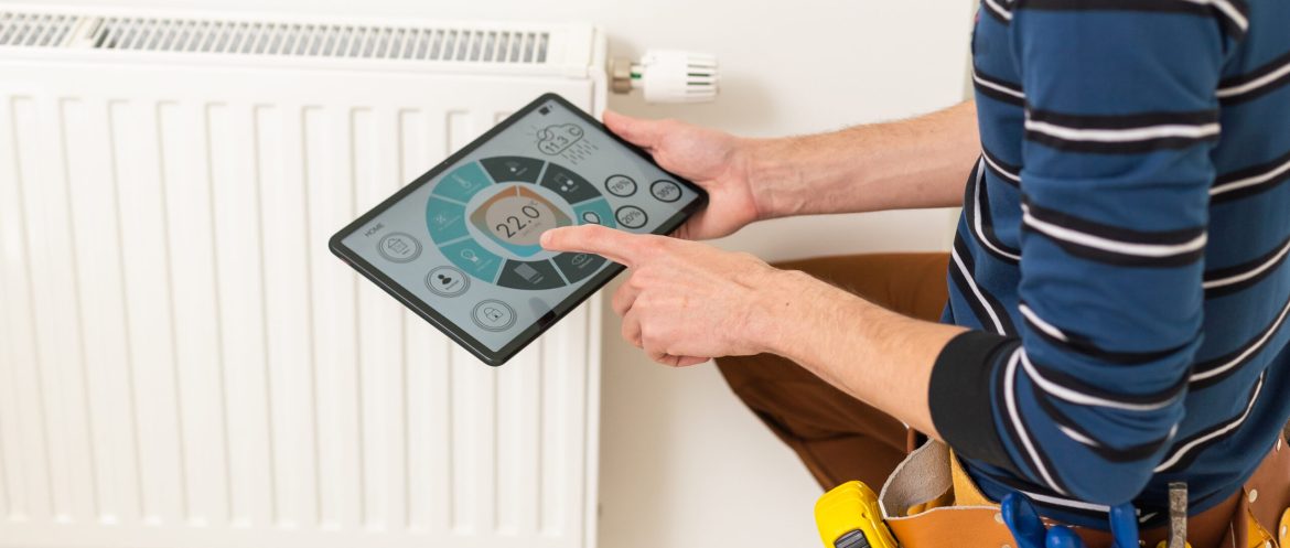 The technician checking the heating system in the boiler room with tablet in hand.